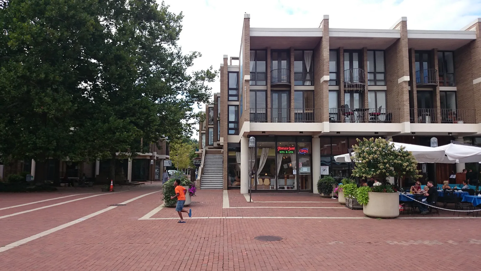 Outdoor tables and umbrellas on the brick plaza at Lake Anne Village Center in Reston