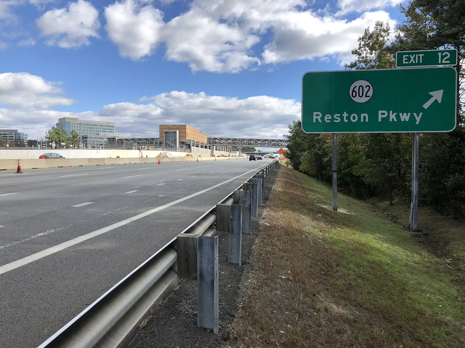 The Dulles Toll Road eastbound at Exit 12 for Reston Parkway, with Reston's office towers ahead